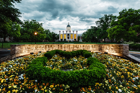 Storm clouds over jesse hall and mizzou columns with MU spelled with green bushes