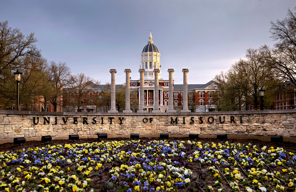 University of Missouri Sign made of black letters on stone wall with mizzou columns and jesse hall