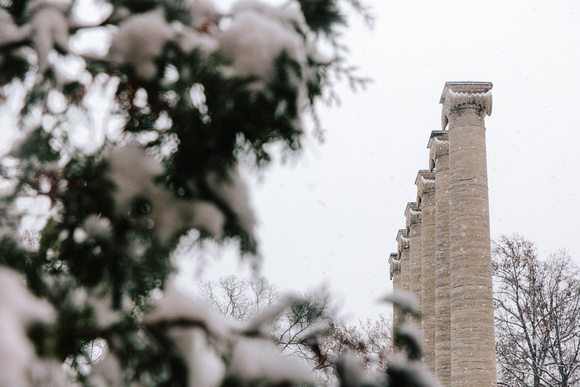 Mizzou Columns covered in snow with evergreen tree