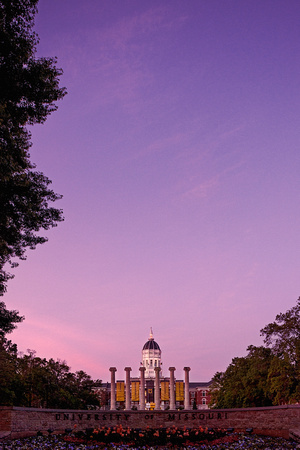 Scenic shot of the University of Missouri sign with the Mizzou Columns and Jesse Hall in the distance at sunrise